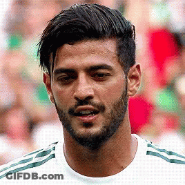 A Man With A Beard Wearing A White Shirt With Green Stripes GIF