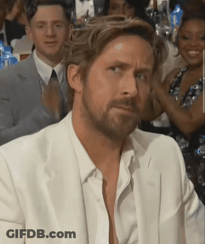 A Man With A Beard Wearing A White Suit Looks At The Camera GIF