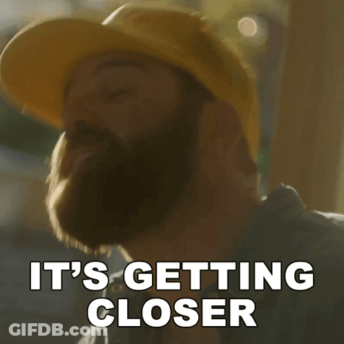 A Man With A Beard Wearing A Yellow Hard Hat Says It 'S Getting Closer GIF