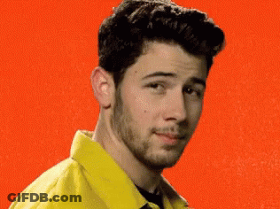 A Man With A Beard Wearing A Yellow Jacket And A Black Shirt Is Smiling . GIF