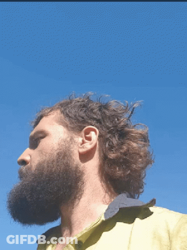 A Man With A Beard Wearing A Yellow Shirt Looks To The Side GIF