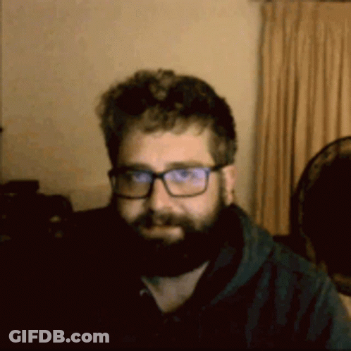 A Man With A Beard Wearing Glasses And A Black Shirt GIF