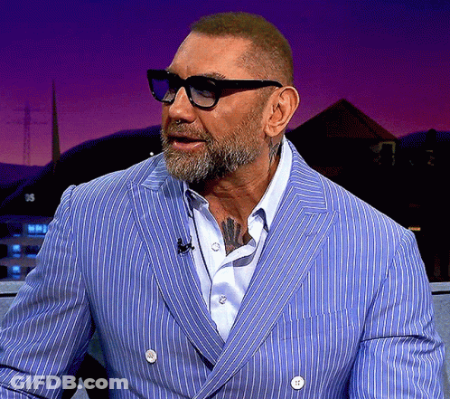 A Man With A Beard Wearing Glasses And A Blue Striped Jacket GIF