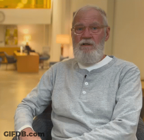 A Man With A Beard Wearing Glasses And A Grey Shirt Gives A Thumbs Up GIF