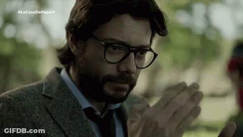 A Man With A Beard Wearing Glasses And A Suit Is Clapping His Hands . GIF