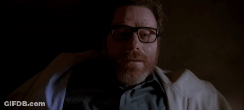 A Man With A Beard Wearing Glasses And A White Coat Is Laying Down In A Dark Room . GIF