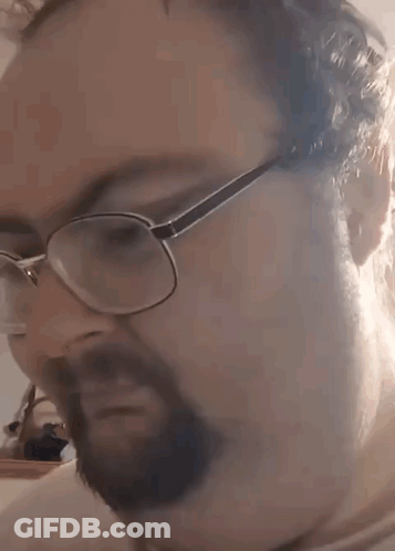 A Man With A Beard Wearing Glasses Is Making A Funny Face . GIF