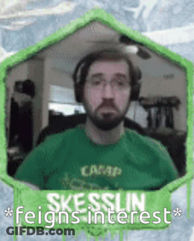 A Man With A Beard Wearing Headphones And A Green Shirt With The Words Skesslin Feigns Interest GIF