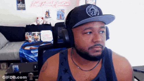 A Man With A Beard Wearing Headphones And A Hat Is Sitting In Front Of A Computer . GIF