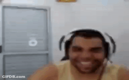 A Man With A Beard Wearing Headphones And A Headset Is Smiling . GIF