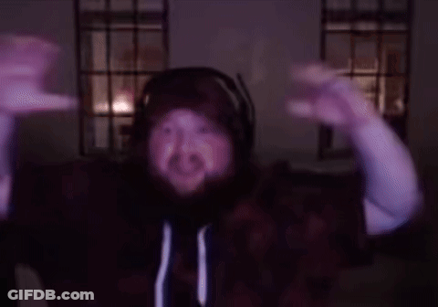 A Man With A Beard Wearing Headphones And A Hoodie Is Dancing In A Dark Room GIF