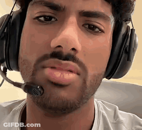A Man With A Beard Wearing Headphones And A Microphone Around His Neck . GIF