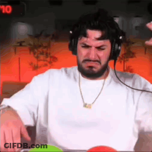 A Man With A Beard Wearing Headphones And A Necklace Is Making A Face . GIF