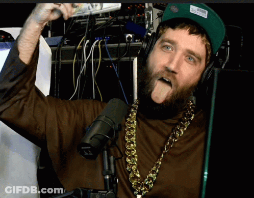A Man With A Beard Wearing Headphones And A Shure Microphone Sticking Out His Tongue GIF