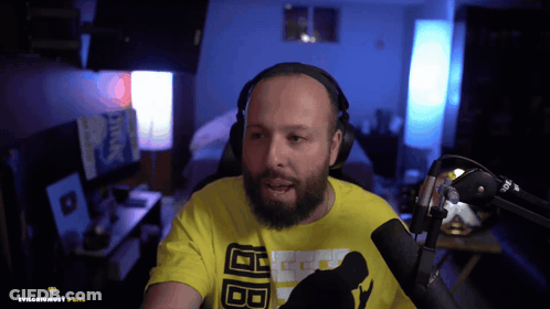 A Man With A Beard Wearing Headphones And A Yellow T-Shirt With The Letters Bb On It GIF