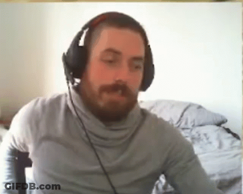 A Man With A Beard Wearing Headphones Is Sitting In Front Of A Computer . GIF