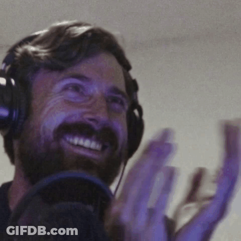 A Man With A Beard Wearing Headphones Is Smiling And Clapping GIF