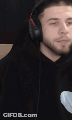 A Man With A Beard Wearing Headphones Looks To The Side GIF