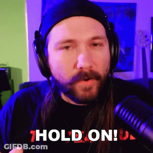 A Man With A Beard Wearing Headphones Says " Hold On " GIF