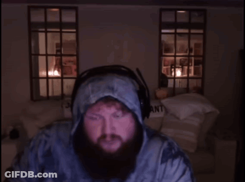 A Man With A Beard Wearing Headphones Stands In Front Of A Sign That Says Part My Pant GIF
