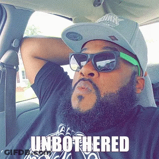 A Man With A Beard Wearing Sunglasses And A Hat Has The Word Unbothered On His Shirt GIF