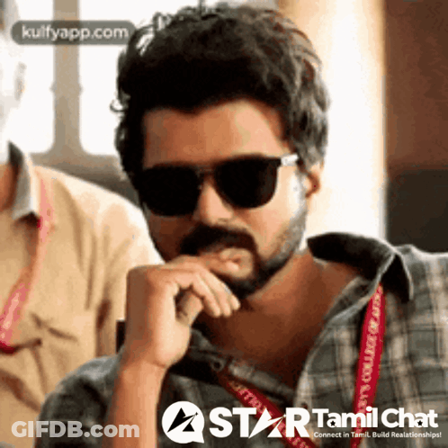 A Man With A Beard Wearing Sunglasses And A Plaid Shirt Is Sitting With His Hand On His Chin . GIF