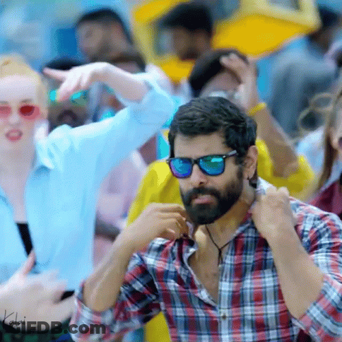 A Man With A Beard Wearing Sunglasses And A Plaid Shirt Is Standing In A Crowd GIF