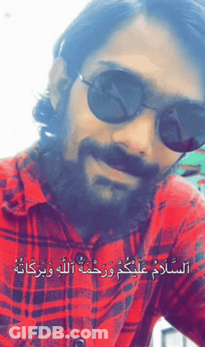 A Man With A Beard Wearing Sunglasses And A Plaid Shirt With Arabic Writing GIF