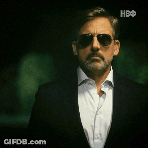 A Man With A Beard Wearing Sunglasses And A Suit With The Hbo Logo Behind Him GIF