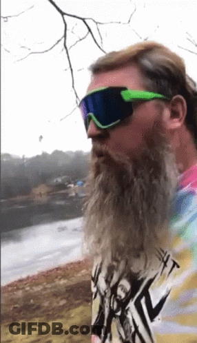 A Man With A Beard Wearing Sunglasses And A Tie Dye Shirt With A Picture Of A Man On It GIF