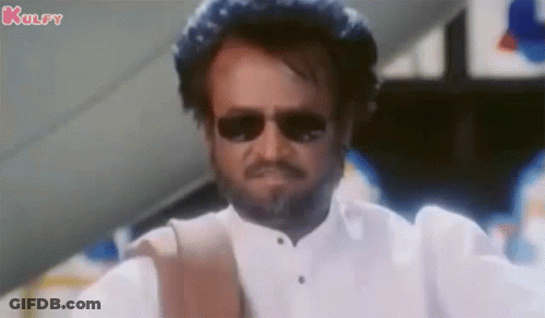 A Man With A Beard Wearing Sunglasses And A White Shirt Is Making A Funny Face . GIF