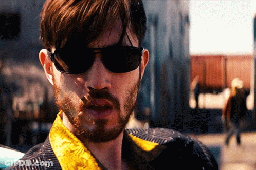 A Man With A Beard Wearing Sunglasses And A Yellow Jacket GIF