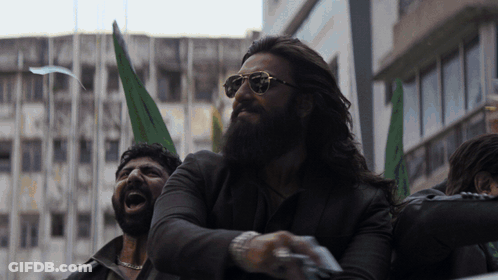 A Man With A Beard Wearing Sunglasses And Holding A Green Flag GIF