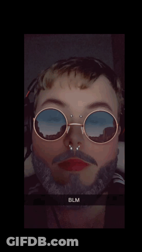 A Man With A Beard Wearing Sunglasses With A Reflection Of Mountains GIF