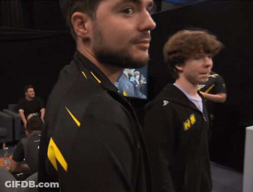 A Man With A Beard Wears A Black And Yellow Jacket That Says Nm GIF