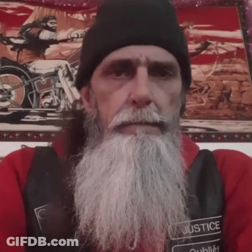 A Man With A Beard Wears A Black Vest With The Word Justice On It GIF
