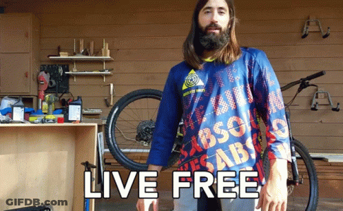 A Man With A Beard Wears A Blue Shirt That Says Live Free GIF