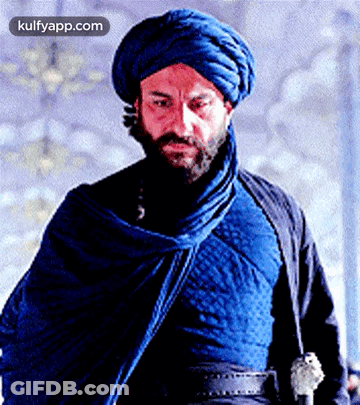 A Man With A Beard Wears A Blue Turban And A Blue Cloak GIF