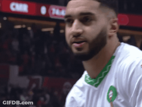 A Man With A Beard Wears A White Shirt With A Green Trim GIF