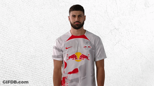 A Man With A Beard Wears A White Shirt With A Red Bull On It GIF