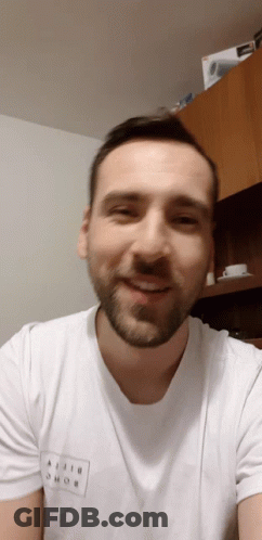 A Man With A Beard Wears A White T-Shirt That Says Ajiji Shob On It GIF