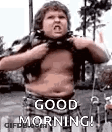 A Man With A Big Belly Is Standing In Front Of A Fence And Saying `` Good Morning '' . GIF