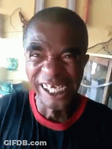 A Man With A Black Shirt And A Red Collar Is Smiling And Looking At The Camera . GIF