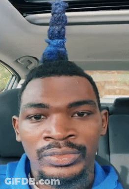A Man With A Blue Mohawk And A Beard Looks At The Camera GIF