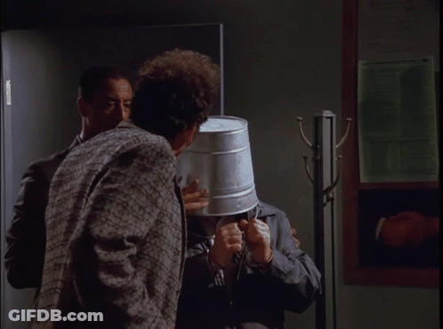 A Man With A Bucket On His Head Is Talking To Another Man With The Words Tell The World My Story Below Him GIF