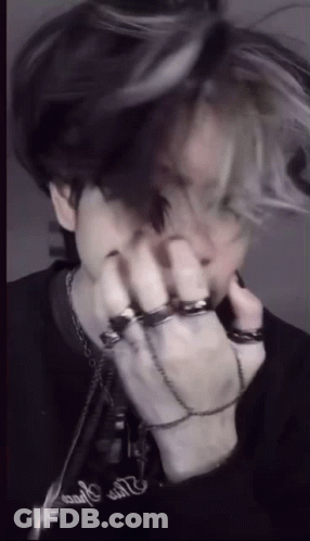 A Man With A Bunch Of Rings On His Hands Is Covering His Face . GIF