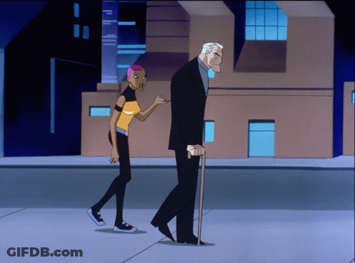 A Man With A Cane And A Woman With Pink Hair Walk Down A Street GIF
