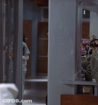 A Man With A Cane Is Standing In A Hallway Next To A Woman GIF