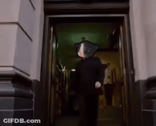 A Man With A Cat On His Head Is Walking Through A Doorway In A Dark Hallway . GIF