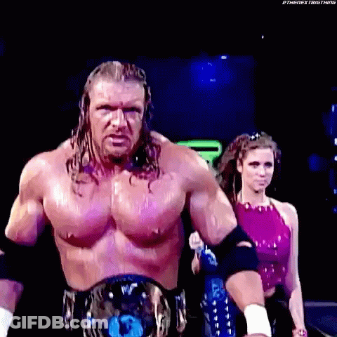 A Man With A Championship Belt Is Walking With A Woman In A Pink Top Behind Him . GIF